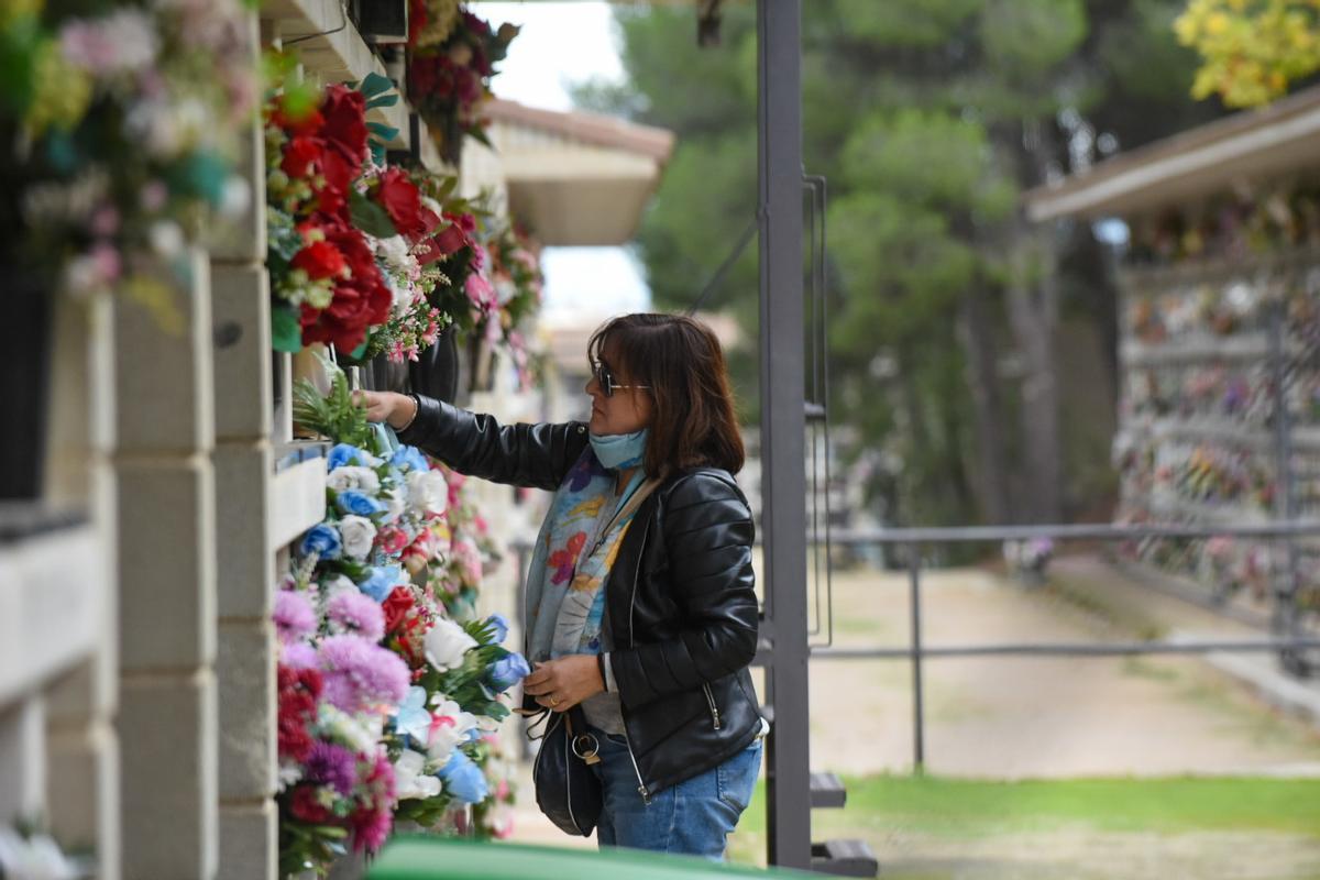 Una mujer cambia las flores, en el cementerio de Torrero.