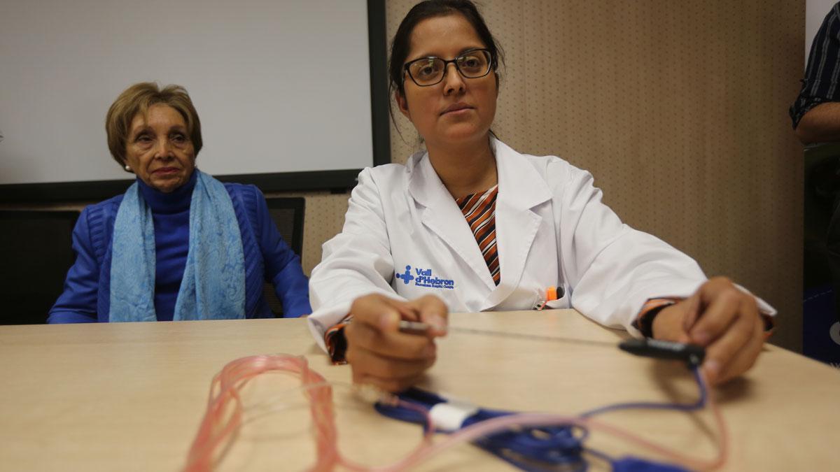 La doctora Elisabeth Pando (derecha) muestra la aguja que se utiliza para la radiofrecuencia intraoperatoria. A la izquierda, la paciente María José. Ambas aparecen en el vídeo comentando la intervención.