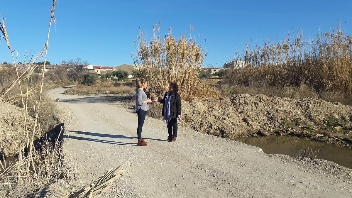 La edil Mari Huertas García con una vecina en el paso sobre el río Vélez.