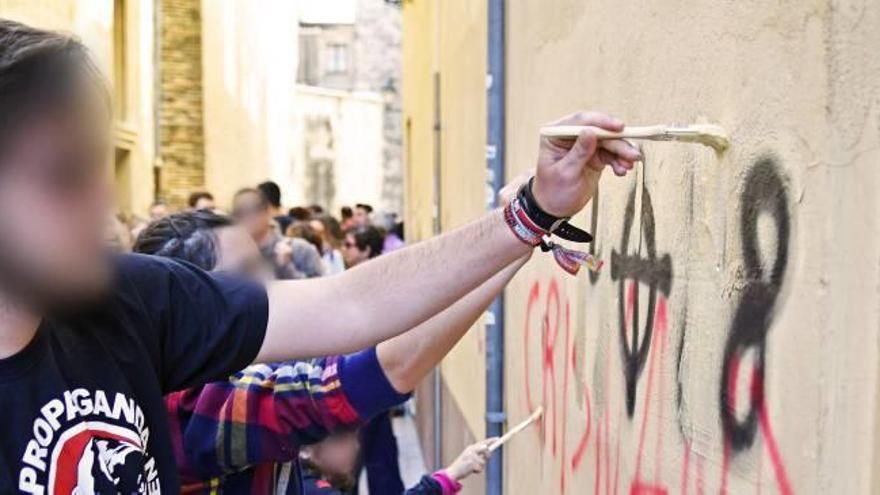 Algunos jóvenes durante la jornada de limpieza de las pintadas de carácter nazi en Alzira.