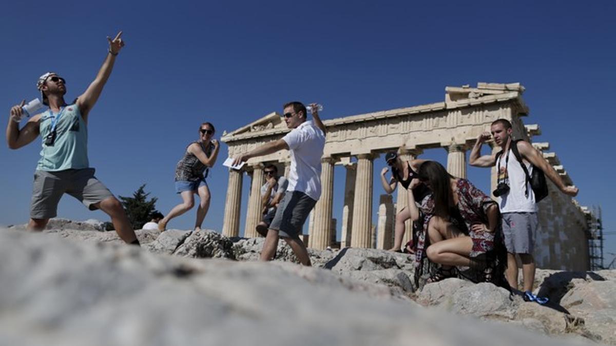 Un grupo de turistas se fotografían frente al Partenón.