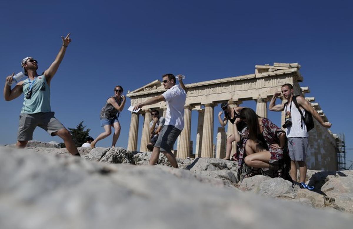 Un grupo de turistas se fotografían frente al Partenón.