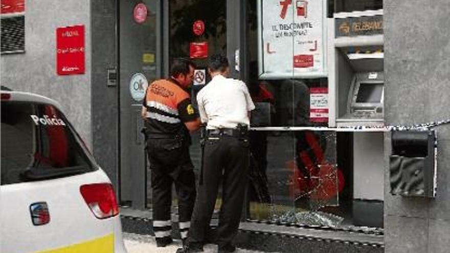 Dos guardes de seguretat acordonant l&#039;oficina bancària on s&#039;ha encastat un cotxe.