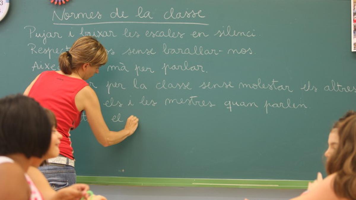 Una profesora escribe las normas de clase, hoy, en el colegio La Sedeta.