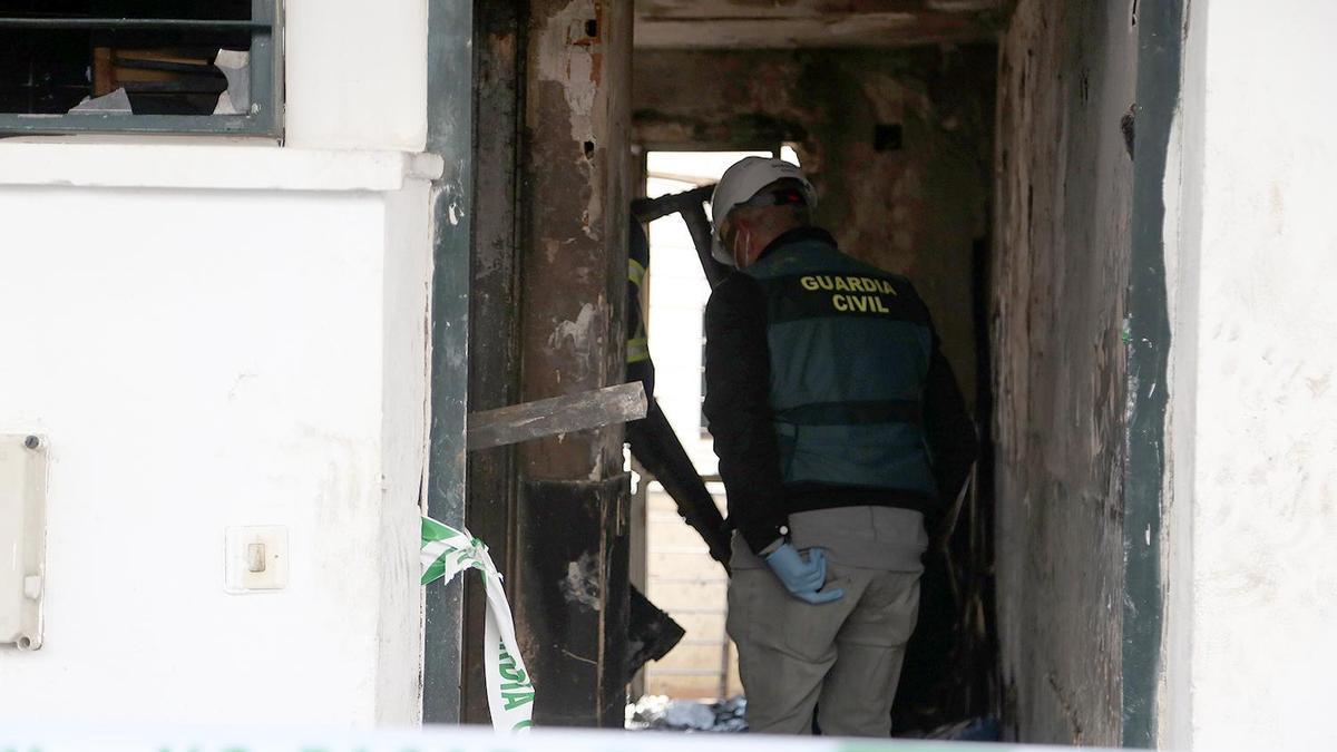 Un guardia civil inspecciona la vivienda siniestrada.