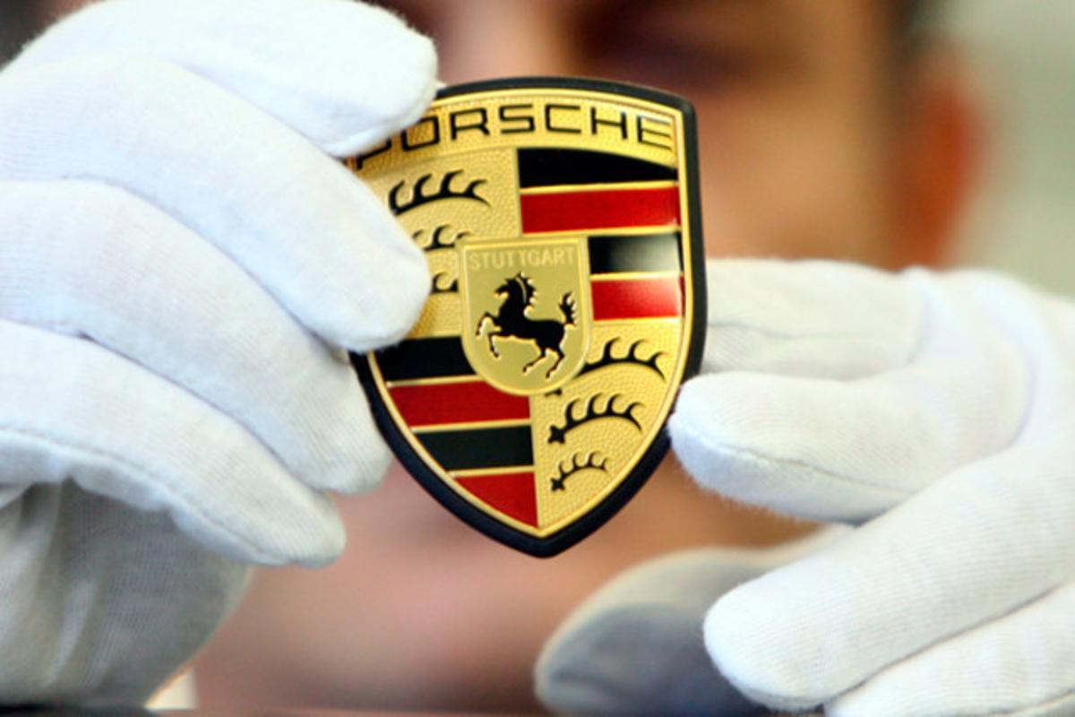 Un mecànic mostra el logo del fabricant alemany d’esportius Porsche a Stuttgart-Zuffenhausen(Alemanya).