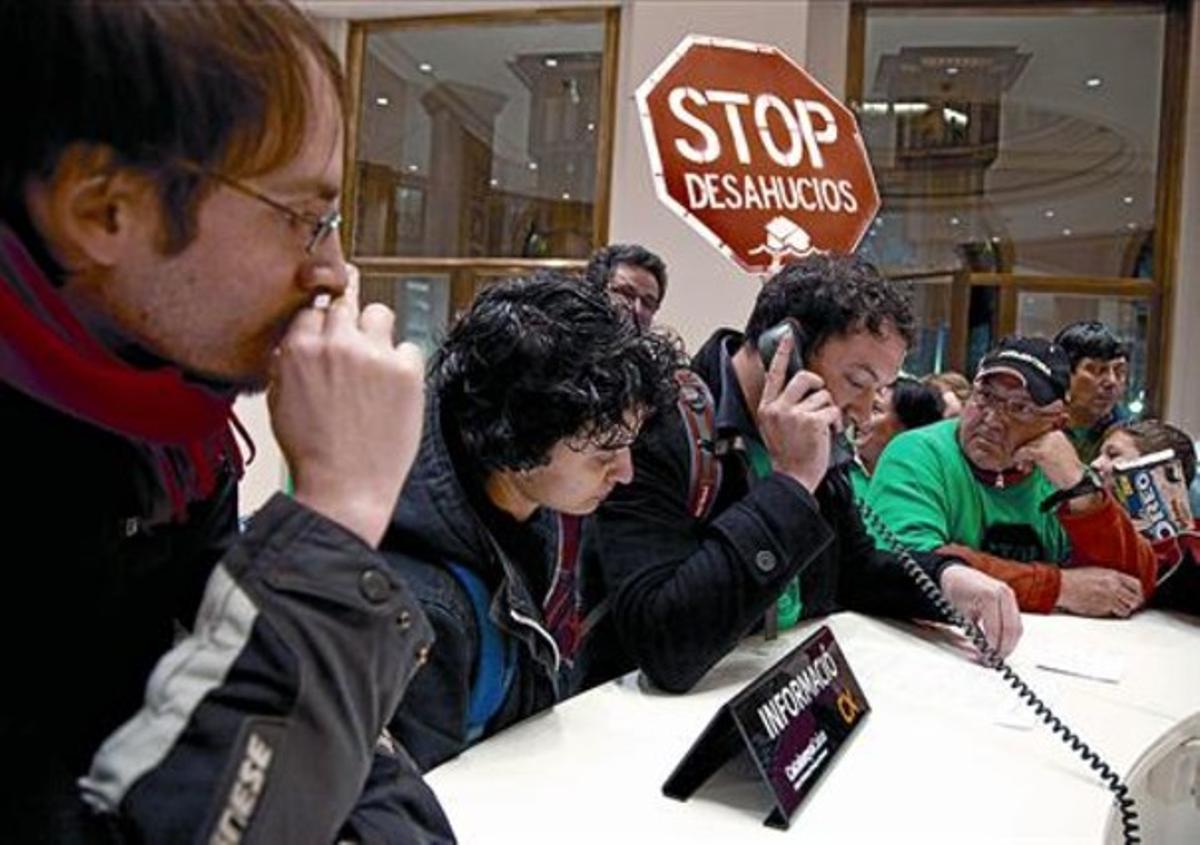 Lluís Martí, con camiseta verde, escucha cómo a Adrià Alemany le atienden por teléfono, ayer en su caja.
