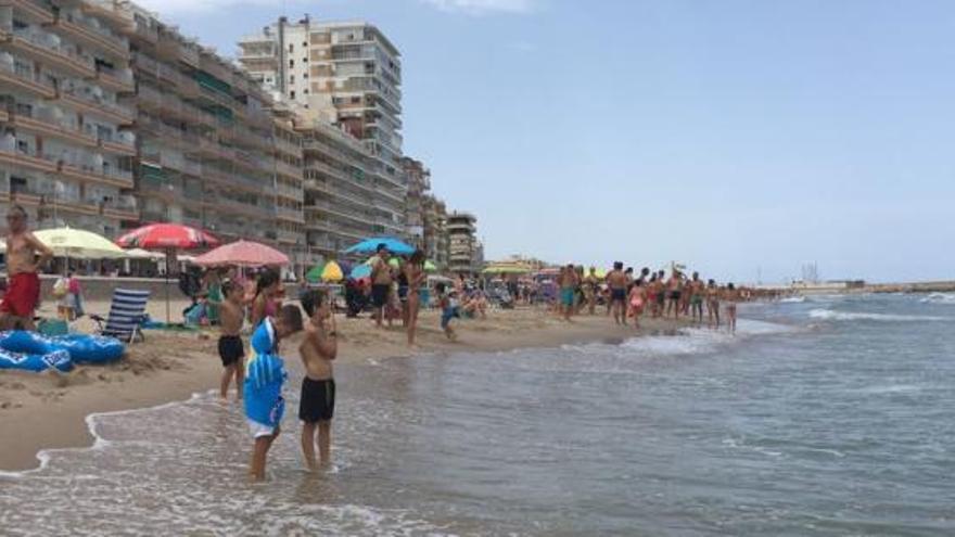 Bañistas contemplando el agua donde ha sido avistado el tiburón en El Perelló