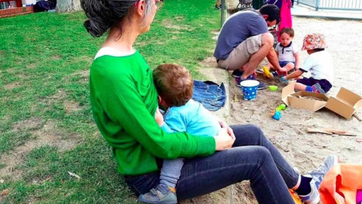 Una madre amamanta a su bebé en un parque de Madrid.