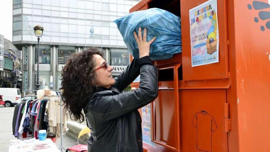 Una mujer dona ropa usada en un contenedor instalado de forma provisional en el Obelisco.