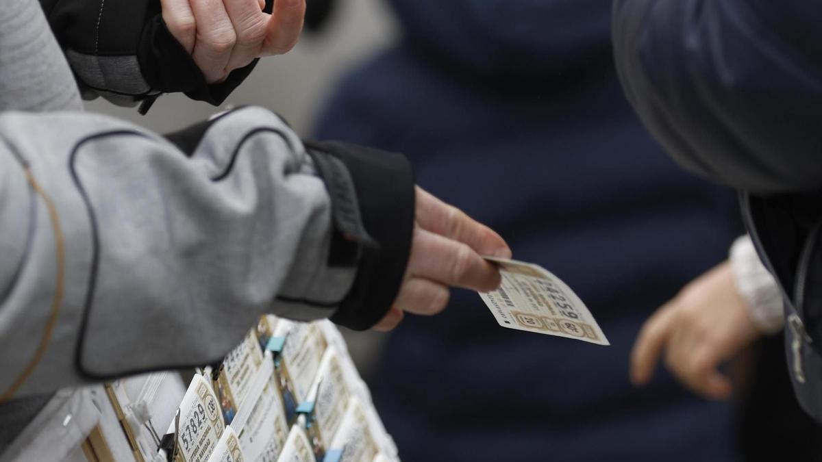 Una personas compra un décimo de lotería de Navidad a una vendedora ambulante cuando quedan menos de tres semanas para el Sorteo Extraordinario de la Lotería de Navidad, a 7 de diciembre de 2021, en Madrid (España). Como cada año, la Lotería de Navidad se
