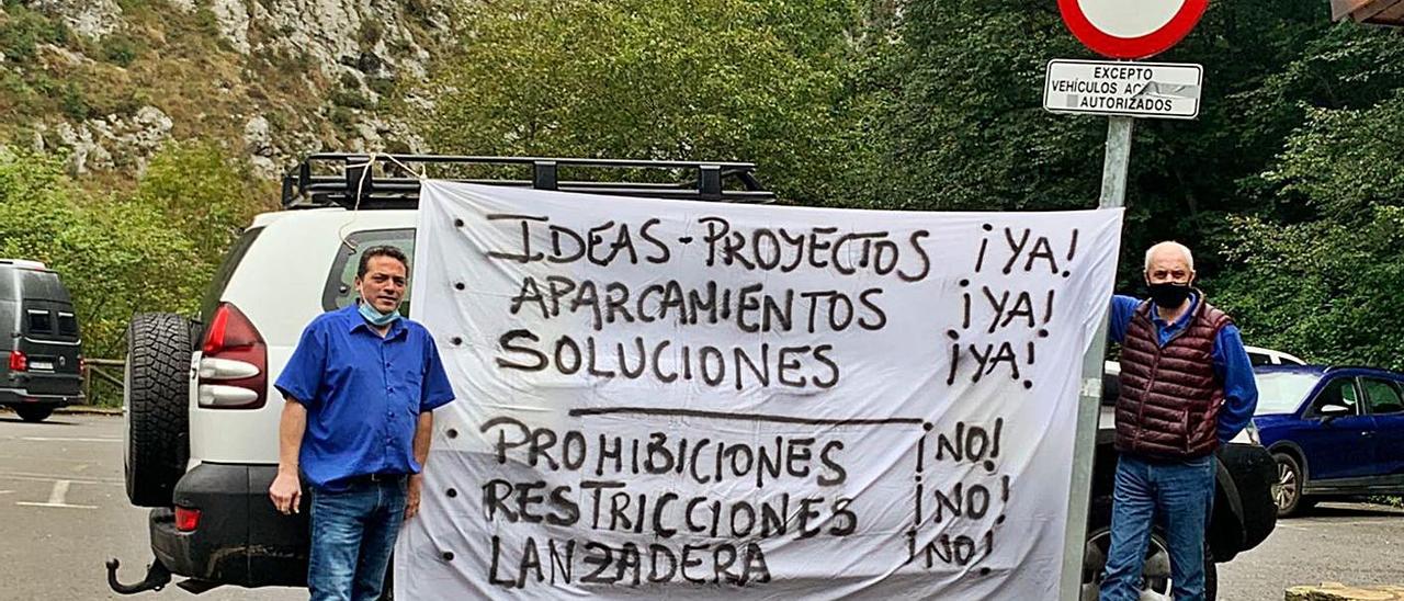 Ramiro Campillo y Francisco García, en el parking de Poncebos, con una pancarta.