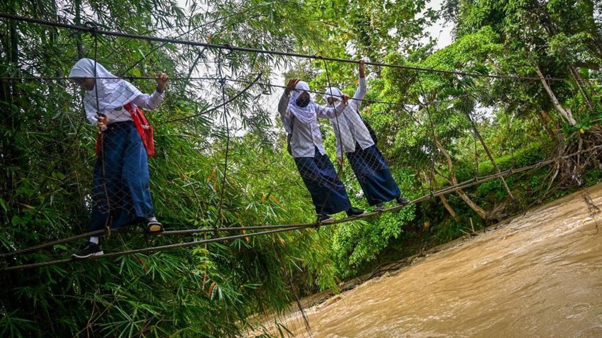 Onze estudiants s’ofeguen mirant de travessar un riu a Indonèsia