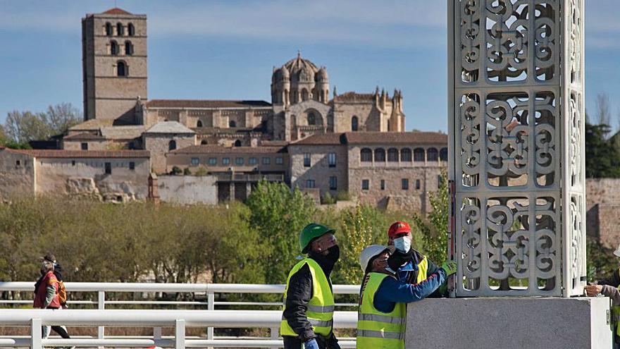 Los operarios fijan el obelisco de aluminio en su pedestal de granito. | Jose Luis Fernández