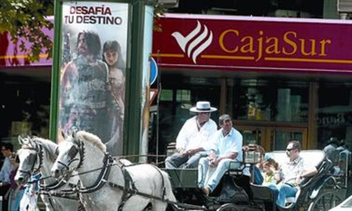 Una família de turistes passegen en un carruatge davant de la seu central de Cajasur a Còrdova, ahir. Una família de turistes passegen en un carruatge davant de la seu central de Cajasur a Còrdova, ahir.