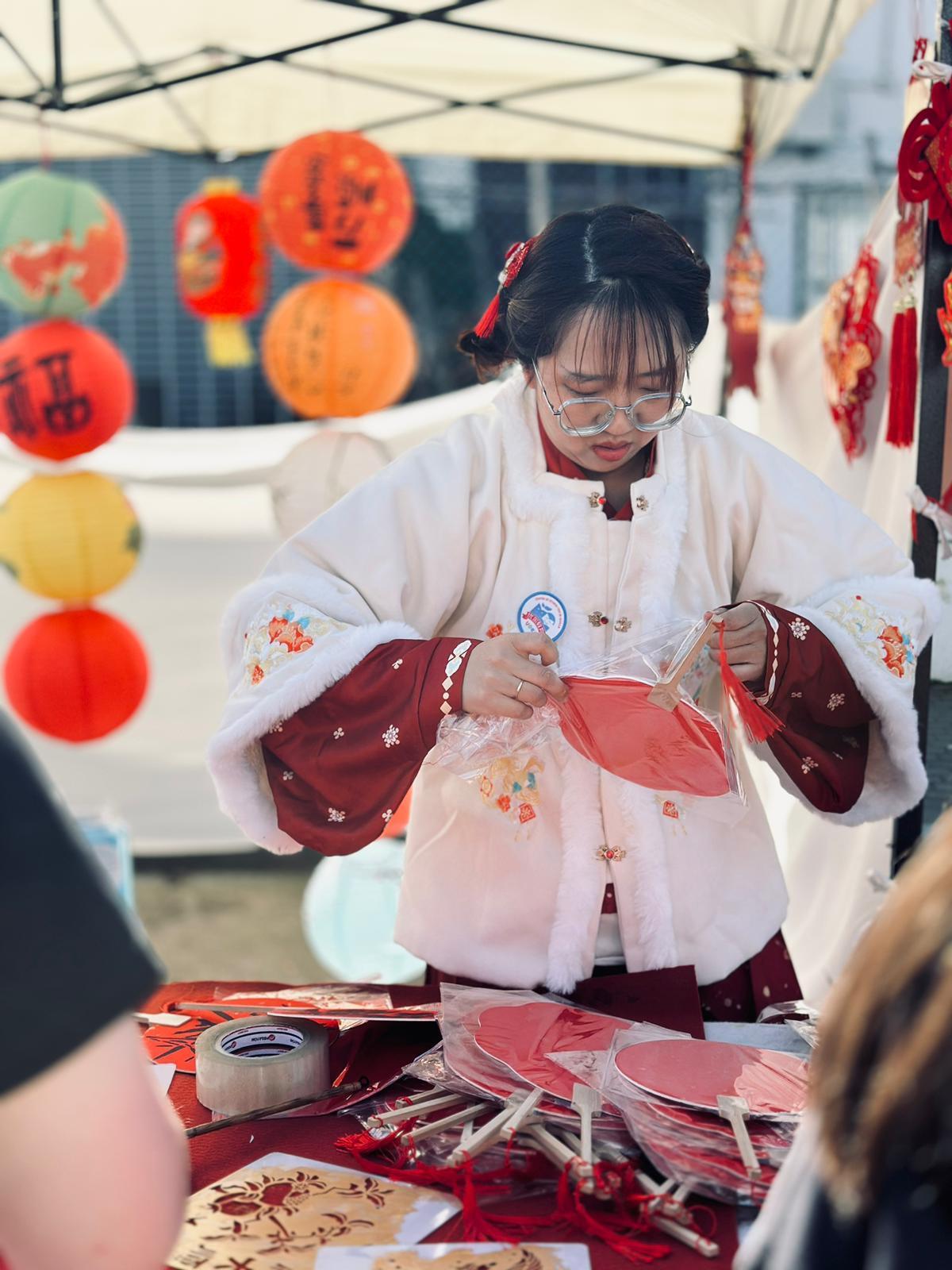 Una comerciante china atiende a los clientes en su puesto de paipays en la feria del Año Nuevo Chino de Sevilla.