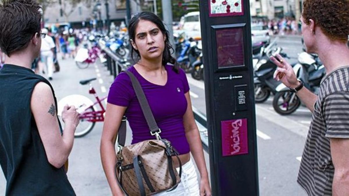 Tres abonados del servicio frente a una parada del Bicing que no funciona en la plaza de Catalunya, ayer.