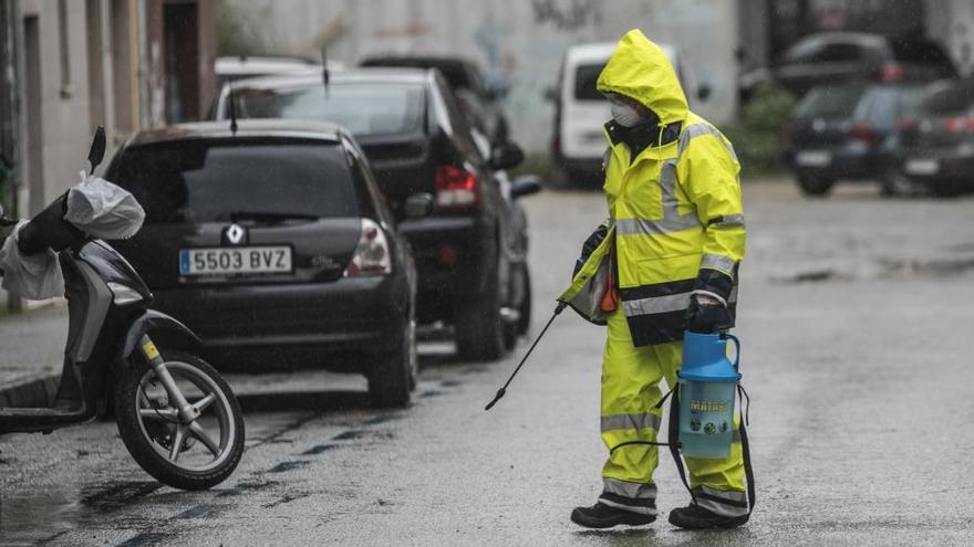 Un trabajador del servicio de limpieza de Siero, desinfecta contenedores en Lugones