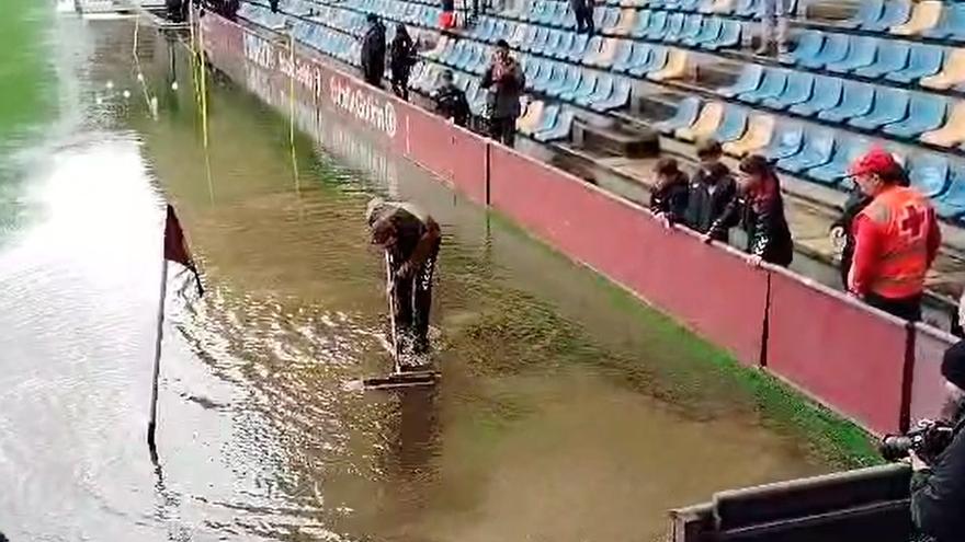 Un operario achica el agua antes del encuentro. 