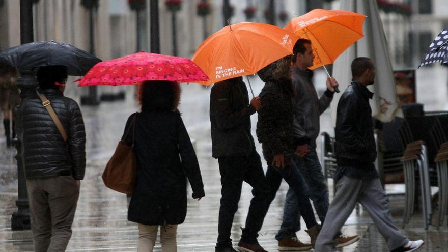 Varias personas pasean bajo la lluvia por el Centro de Málaga.