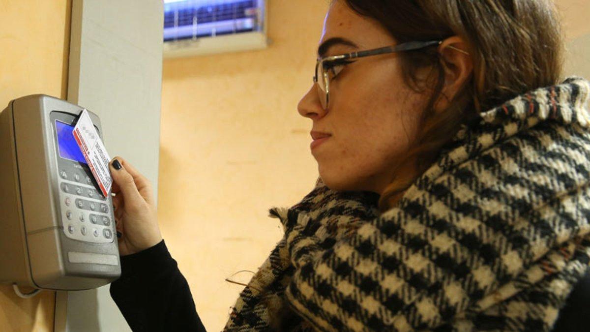 Una trabajadora ficha en un aparato de control horario.