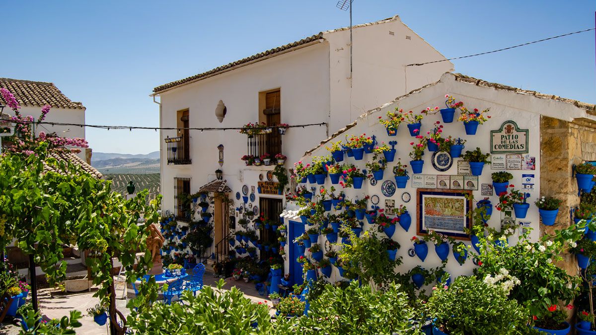 El Patio de las Comedias, uno de los rincones más emblemáticos de Iznájar, luce su tradicional estampa de macetas azules y flores que llenan de color este Pueblo Mágico
