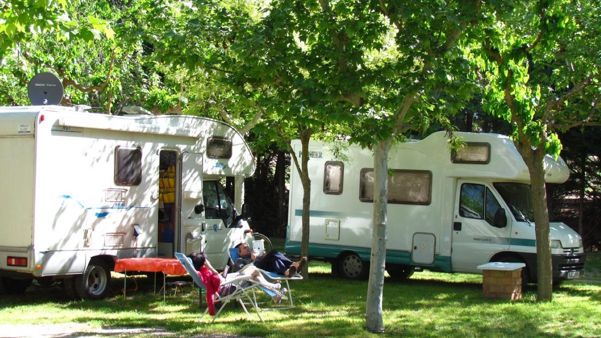 Una pareja descansa en una hamaca cerca de dos autocaravanas