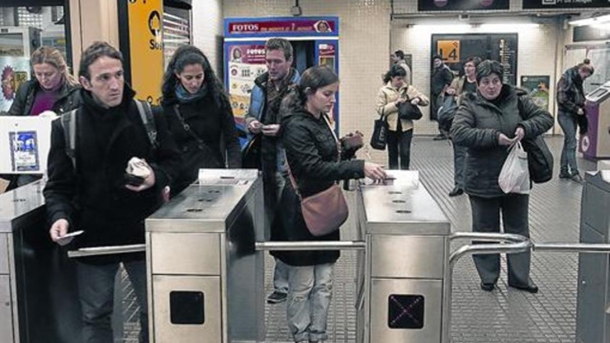 Varios usuarios entran en una estación del metro de Barcelona validando sus títulos de transporte.