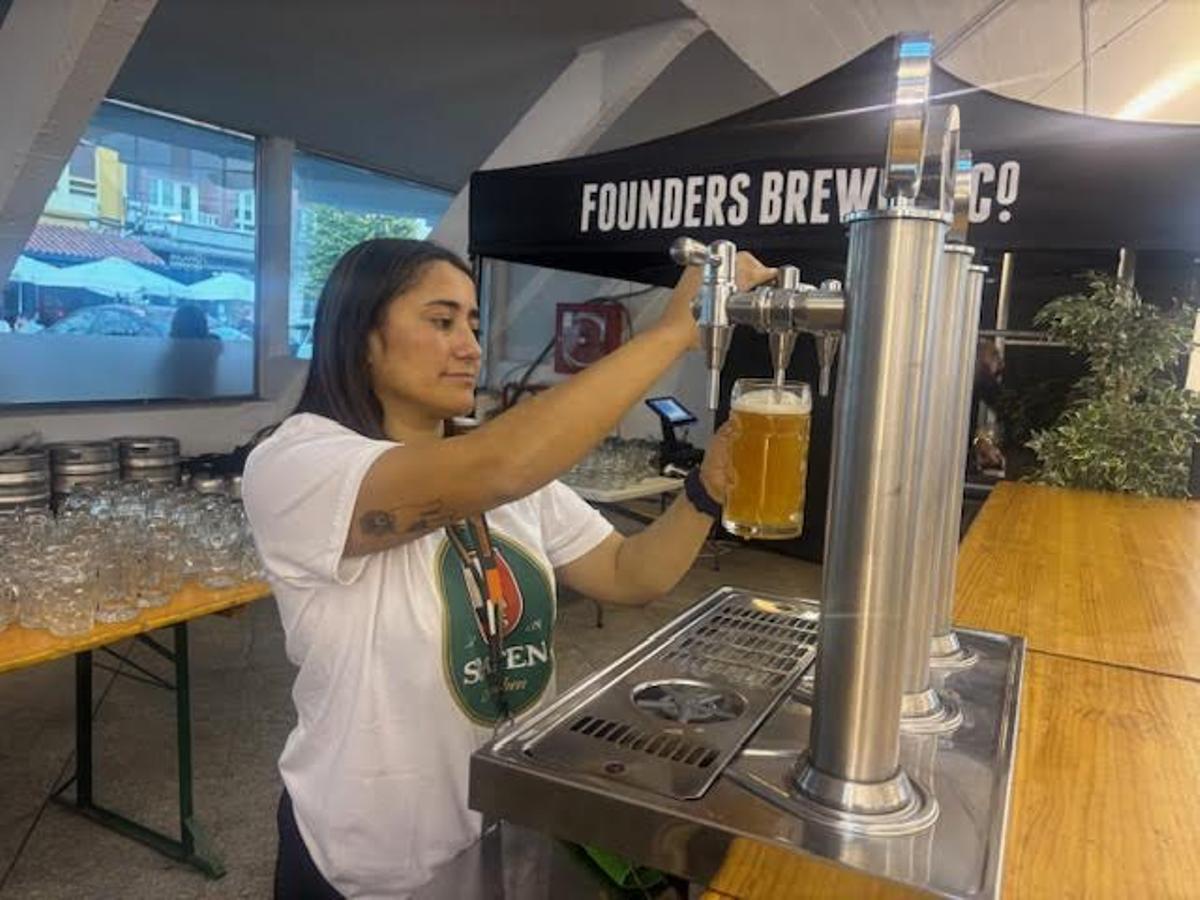 Una camarera sirve una caña.