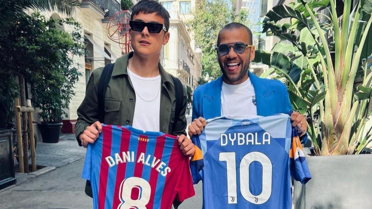 Dani Alves y Paulo Dybala posando junto con la camiseta del otro