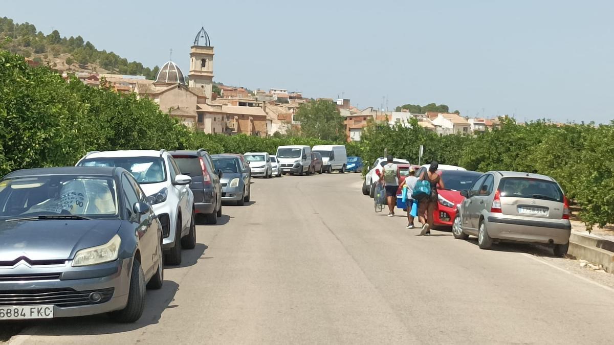 Vehículos estacionados en un camino rural de Antella, con Sumacàrcer al fondo.