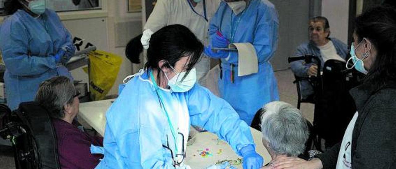 Enfermeras ponen una dosis de vacuna contra el COVID en un geriátrico.  | // FERRAN NADEU