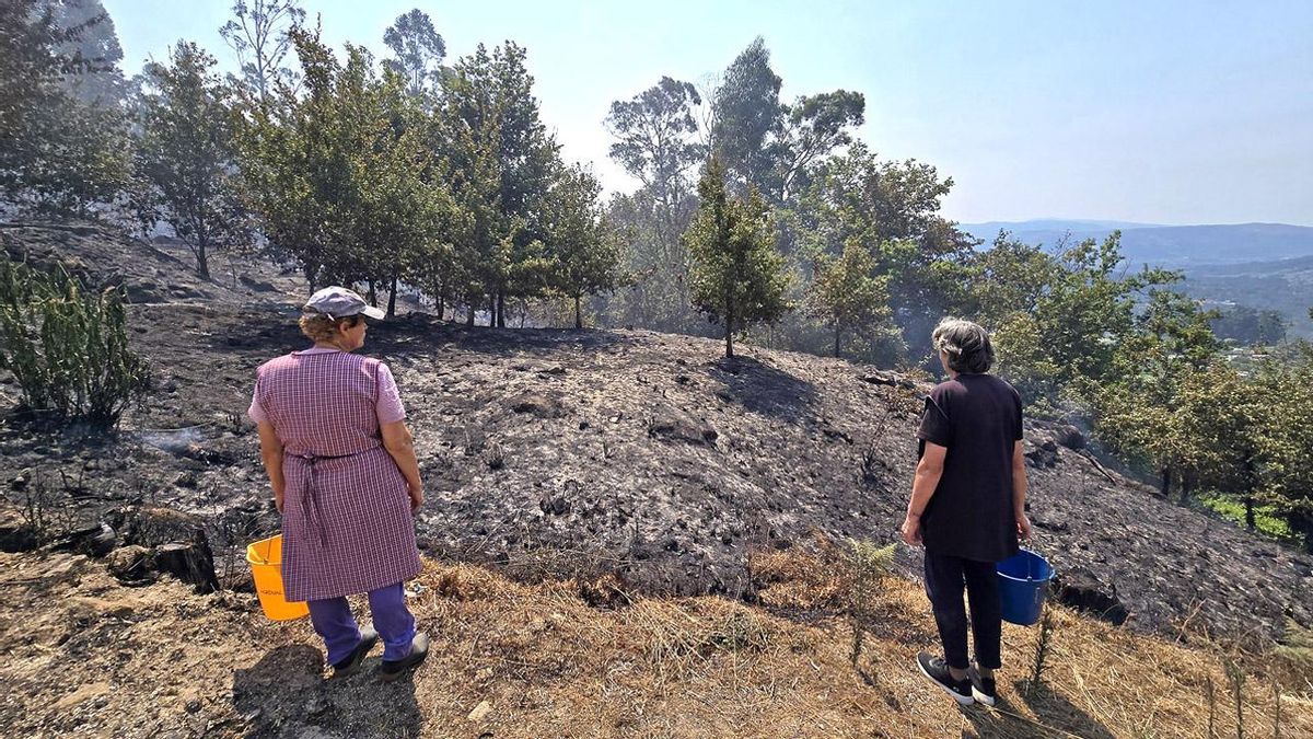 Divina Pérez y Pilar Giráldez, observando la devastación del fuego que cercó sus viviendas en Valeixe