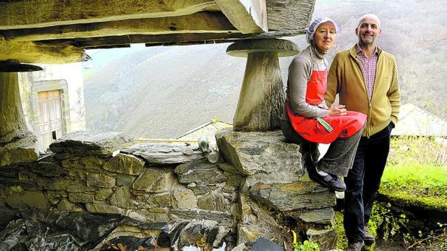 Laura González Rodríguez y Elías García Pérez, sentados junto a un hórreo en el pequeño pueblo de Monón, en Allande.