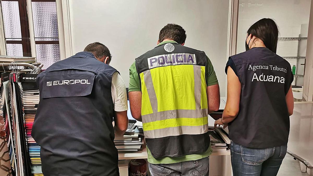 Agentes de la Agencia Tributaria, de la Policía Nacional y de Europol examinan documentación del caso. | LEVANTE-EMV