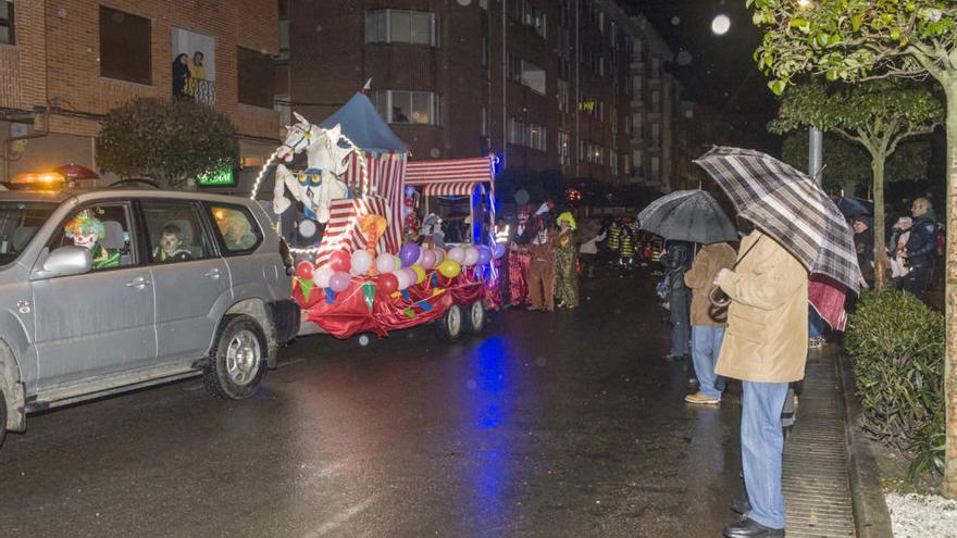 Personas con paraguas ven pasar el desfile de carnaval ayer sábado.