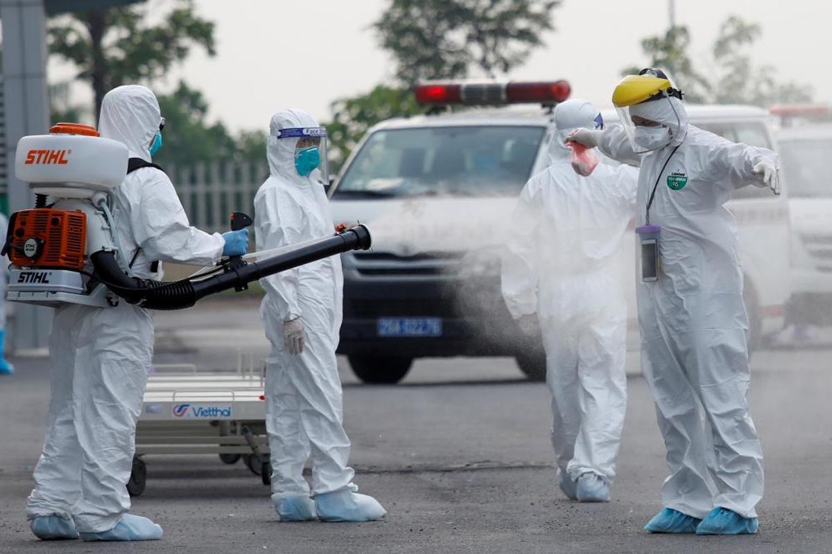 Sanitaris es ruixen un desinfectant després de tractar amb obrers vietnamites infectats amb la Covid-19