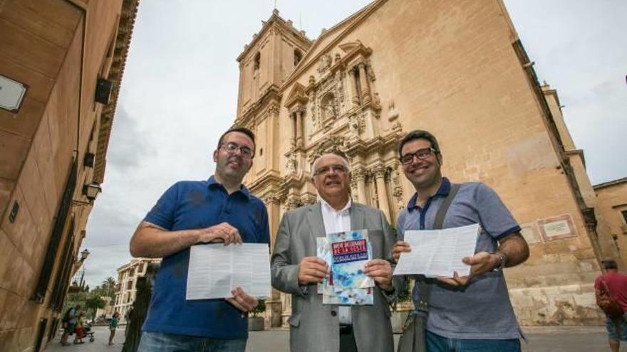 Hèctor Càmara, Fernando García y Pablo Mas, ayer frente a Santa María, con los dípticos. A la derecha, niños echando un vistazo al trabajo realizado por la Cátedra.