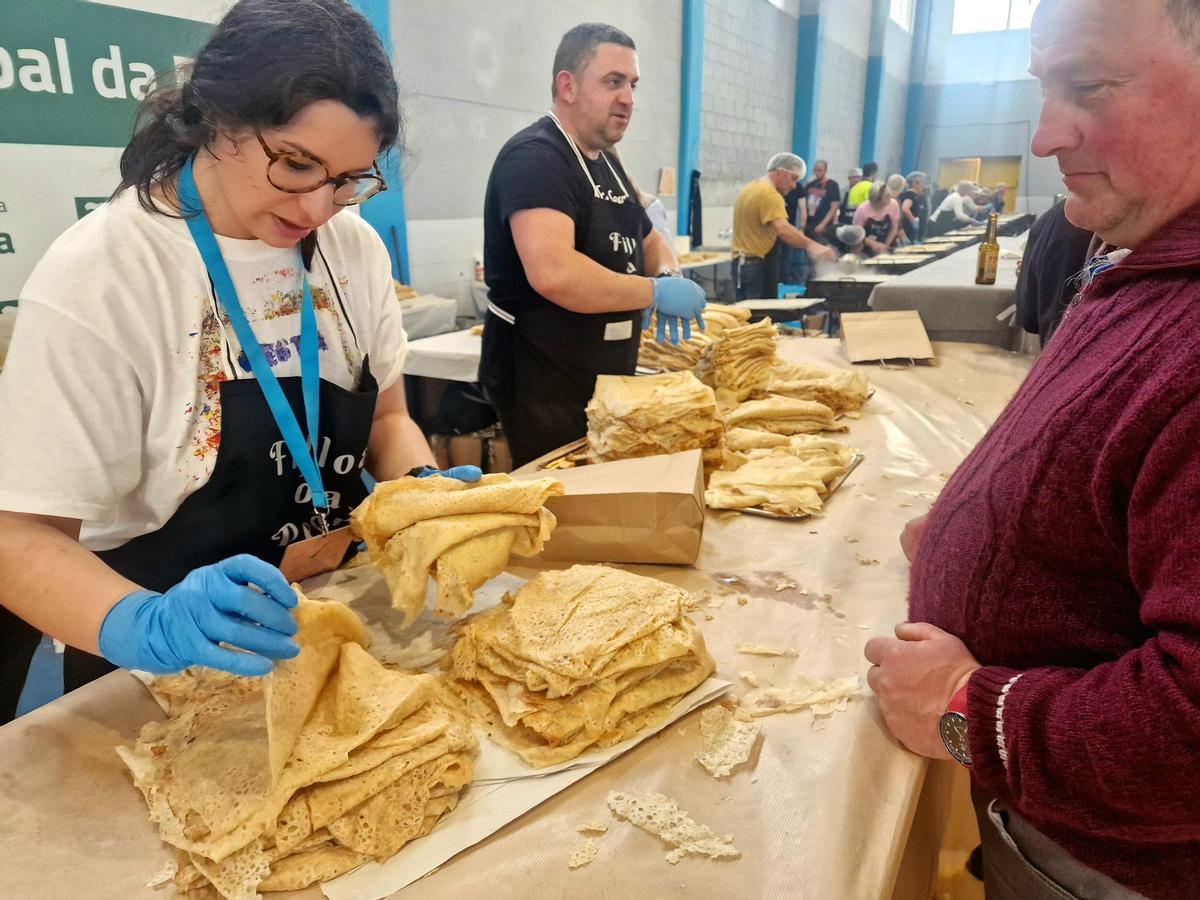 Reparto de filloas á pedra na festa da Baña