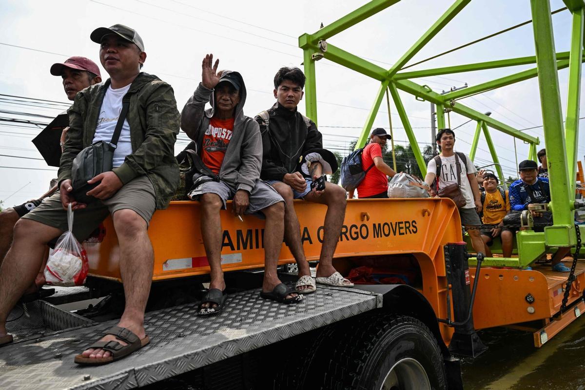 La gente viaja en un camión mientras se mueve a través de una calle inundada después de las fuertes lluvias traídas por el monzón del suroeste en Pampanga el 31 de agosto de 2026. (Foto de Jam STA ROSA / AFP)