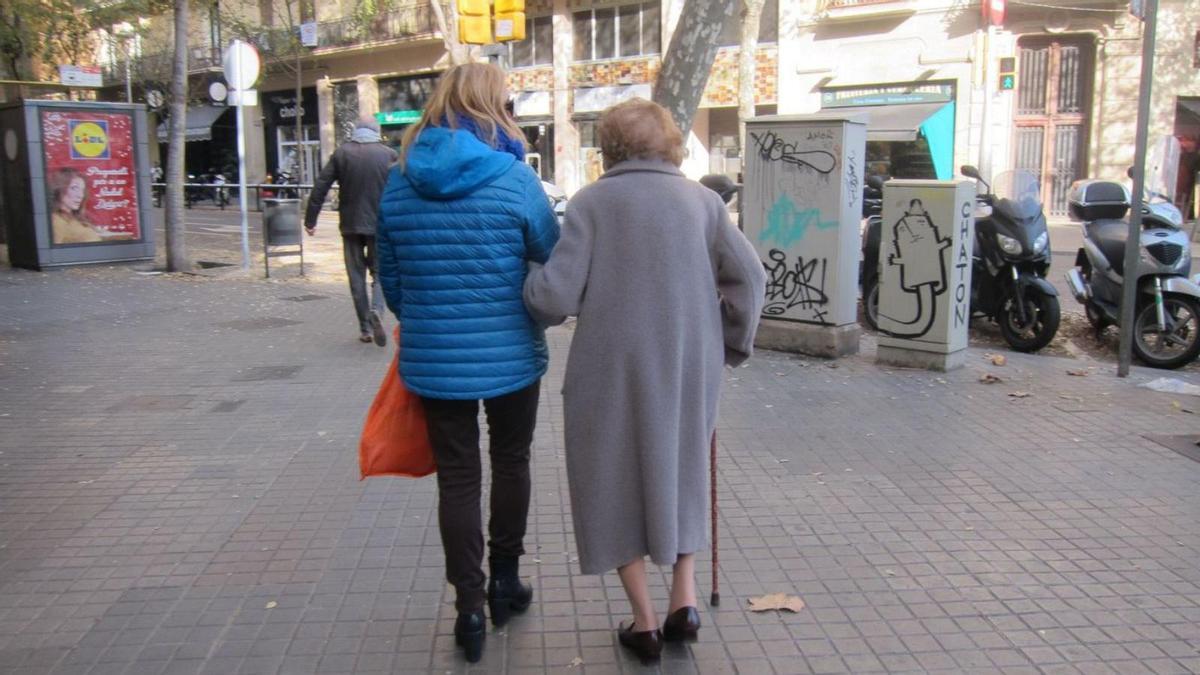 Una anciana acompañada de una cuidadora.