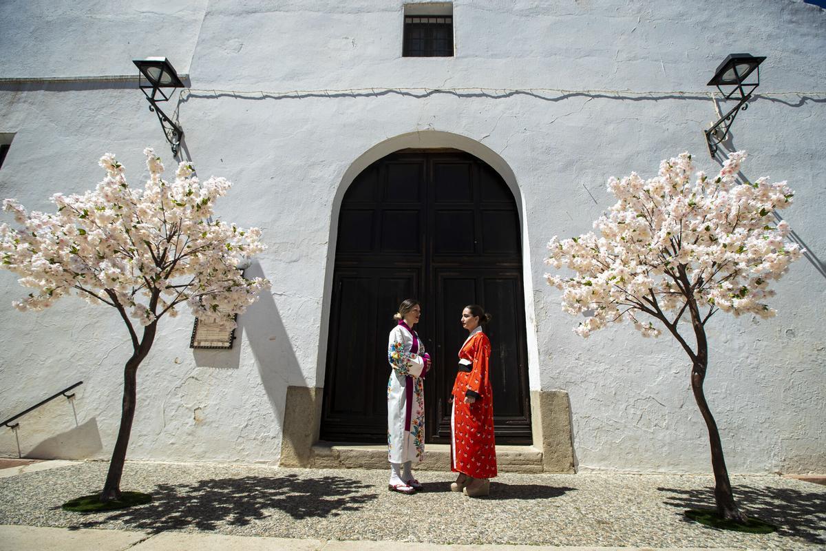 Unas vecinas del pueblo de Alfarnate vestidas con kimonos ante unos cerezos realizado con flores de papel escenifican la celebración del festival de Sakura con la floración de los cerezo.