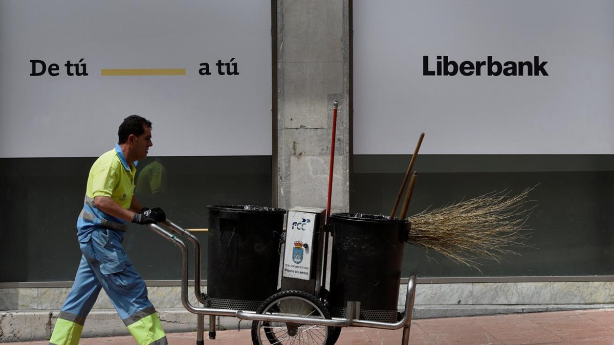 A street cleaner walks in front of a local of Liberbank in Oviedo