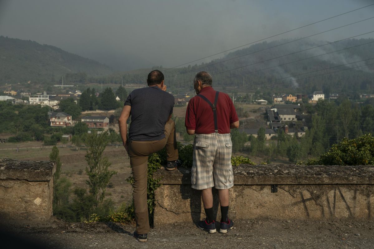 Dos vecinos observan el incendio de Valdeorras en Quereño, Rubiá, el último pueblo que estuvo en peligro.