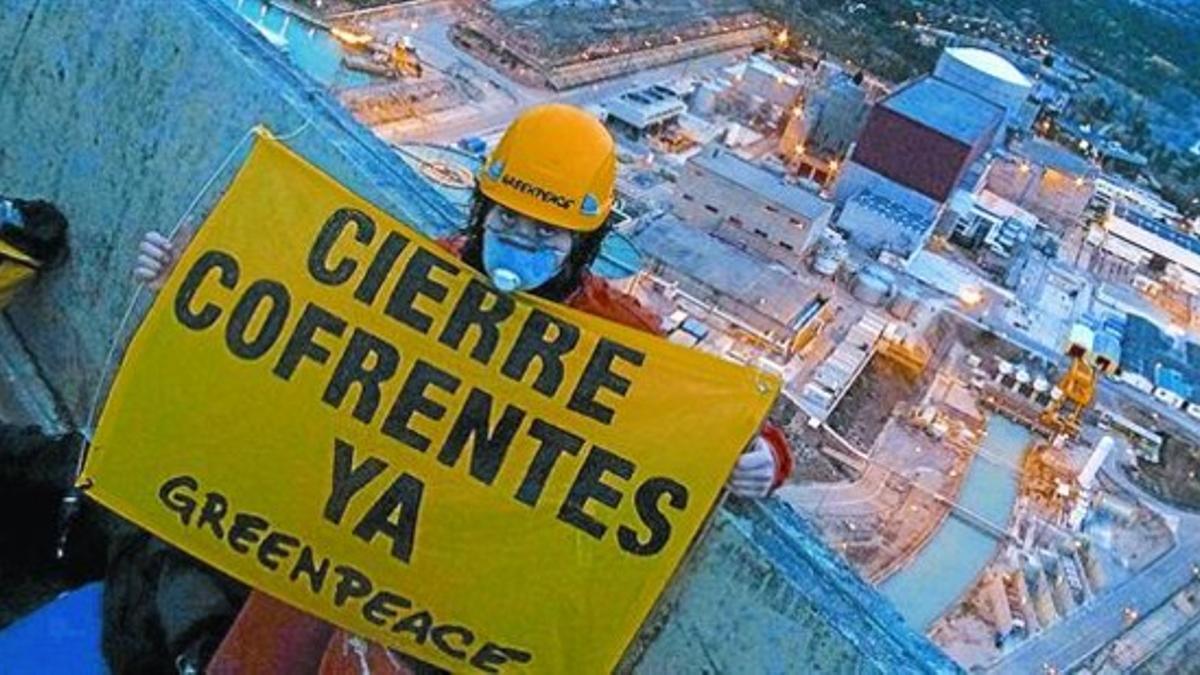 Un activista de Greenpeace, con un cartel en una de las torres de refrigeración de Cofrentes.