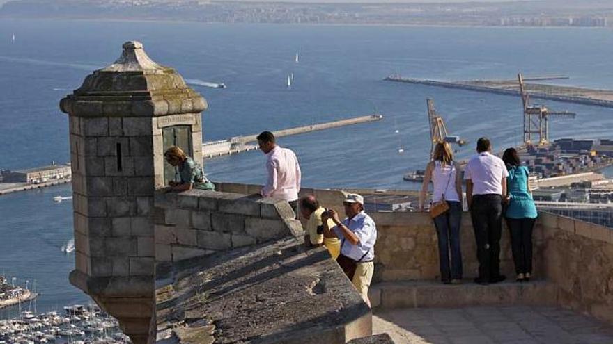 Un grupo de turistas observa el Puerto de Alicante desde el castillo de Santa Bárbara.