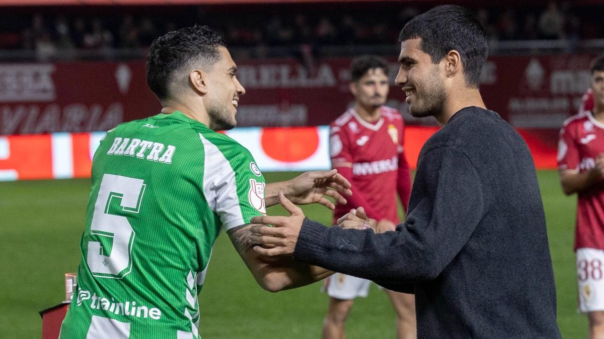 Carlos Alcaraz saluda a Marc Bartra en la previa del Murcia-Betis