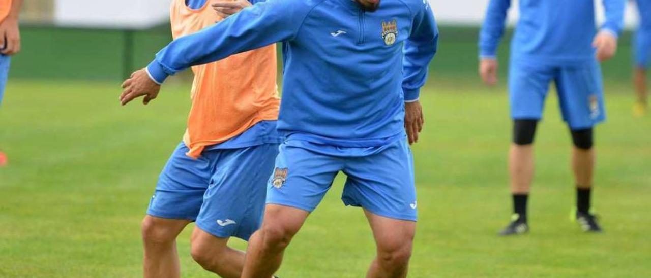 Adrián Mouriño conduce la pelota durante un entrenamiento ante la presión de Jandrín. // Rafa Vázquez