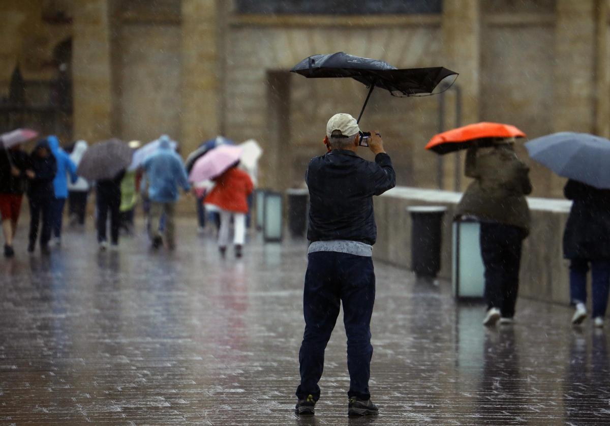 Un viandante toma una fotografía bajo la lluvia en Córdoba.