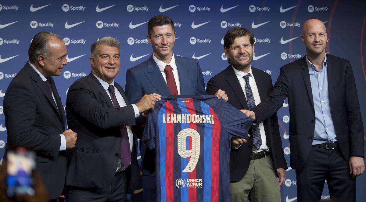 Los directivos Rafa Yuste y Joan Laporta y los ejecutivos Mateo Alemany y Jordi Cruyff a los lados de Lewandowski mostrando el nombre y número 9 de la camiseta del delantero.